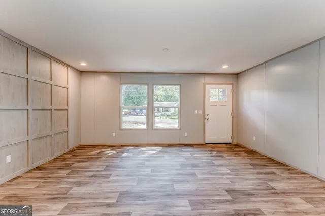 a view of an empty room with wooden floor and a window