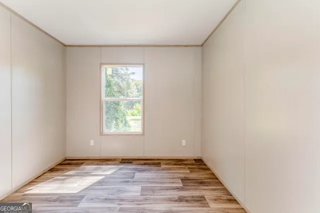 an empty room with wooden floor and window