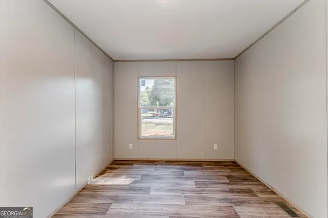 a view of an empty room with wooden floor and window
