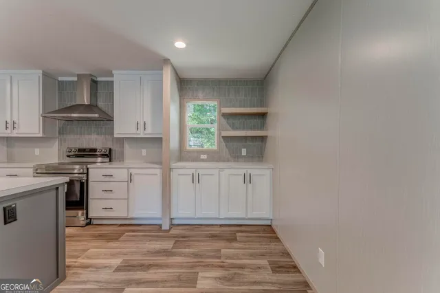 a large kitchen with stainless steel appliances granite countertop a large stove a sink a refrigerator and white cabinets with wooden floor