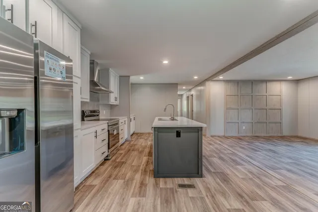 a kitchen with kitchen island wooden floors appliances and cabinets