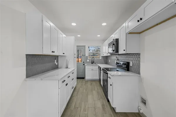 a kitchen with white cabinets sink and stove