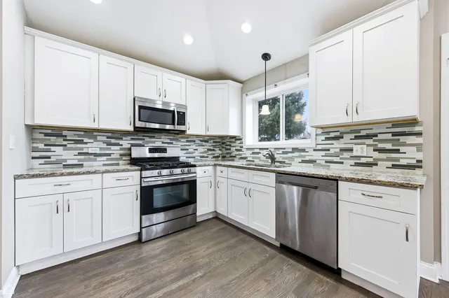 a kitchen with granite countertop white cabinets sink and stainless steel appliances