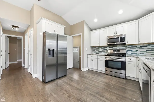 a kitchen with granite countertop a refrigerator and a stove top oven