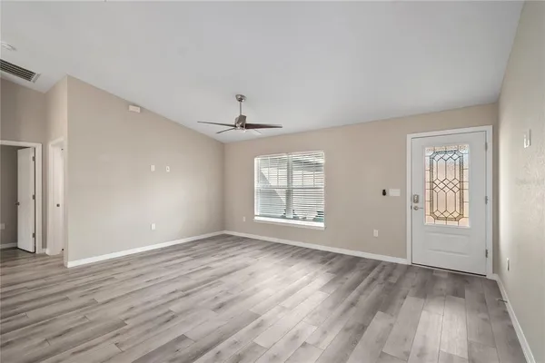 an empty room with wooden floor chandelier and windows
