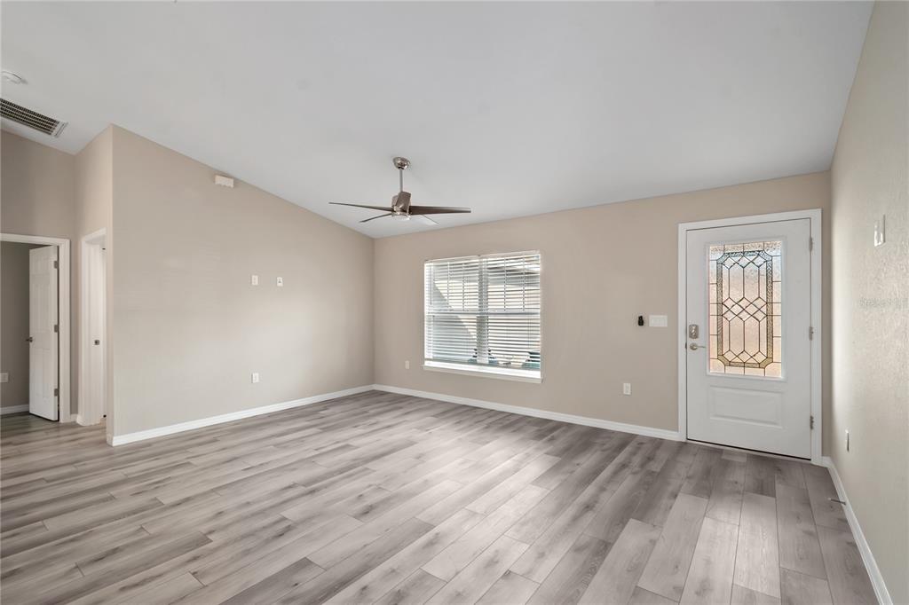 7052 Southwest 179th Ave Road Dunnellon, FL 34432 - Photo 12 of 42 an empty room with wooden floor chandelier and windows