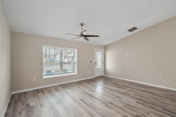a view of an empty room with wooden floor and a window