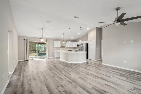 a large white kitchen with wooden floors and kitchen view