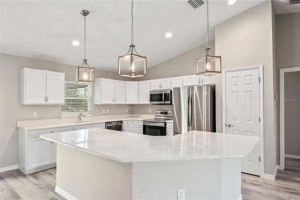 a kitchen with stainless steel appliances granite countertop a sink a stove a refrigerator and island with wooden floor