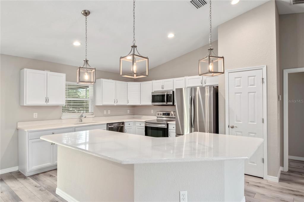 7052 Southwest 179th Ave Road Dunnellon, FL 34432 - Photo 16 of 42 a kitchen with stainless steel appliances granite countertop a sink a stove a refrigerator and island with wooden floor