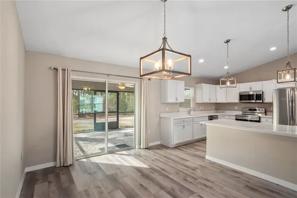 a open kitchen with granite countertop a stove a sink dishwasher a refrigerator and white cabinets with wooden floor