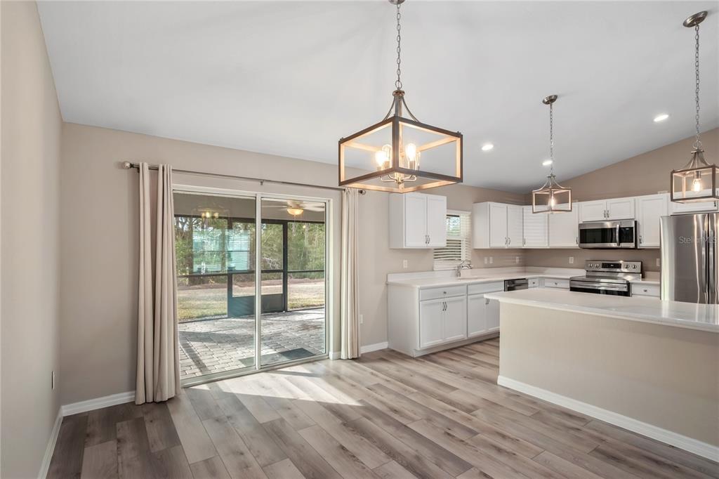 7052 Southwest 179th Ave Road Dunnellon, FL 34432 - Photo 18 of 42 a open kitchen with granite countertop a stove a sink dishwasher a refrigerator and white cabinets with wooden floor