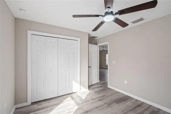 an empty room with wooden floor ceiling fan and windows