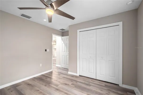 an empty room with wooden floor closet and windows