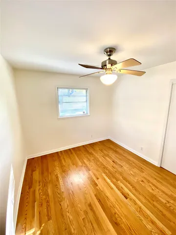 a view of a room with wooden floor and a ceiling fan