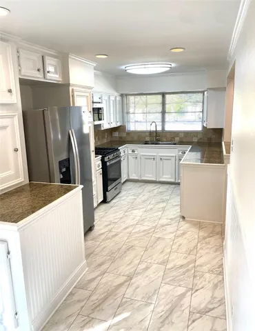 a kitchen with stainless steel appliances a refrigerator a stove a sink a counter top space and cabinets