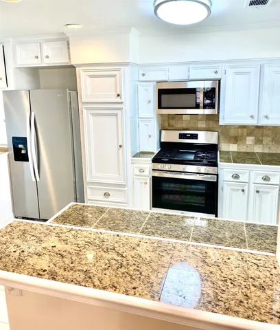 a kitchen with granite countertop a refrigerator and a stove top oven