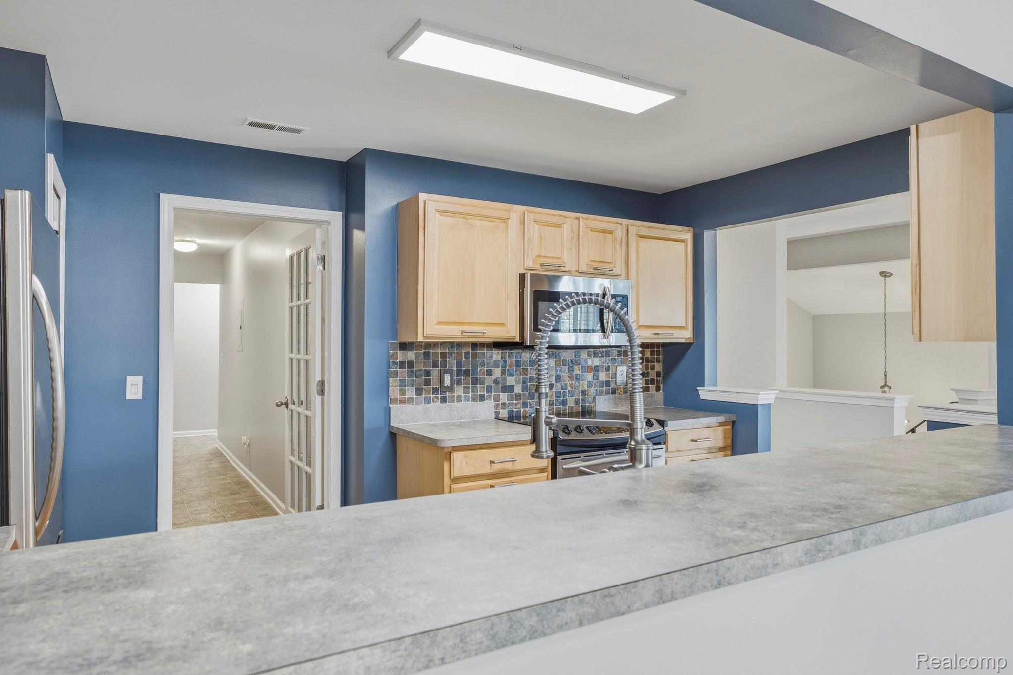 1905 Flagstone Circle Rochester, MI 48307 - Photo 14 of 33 Spacious kitchen featuring light wood cabinetry, a mosaic tile backsplash, a stainless steel microwave, and a gooseneck faucet