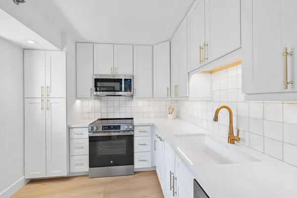 a kitchen with white cabinets and stainless steel appliances