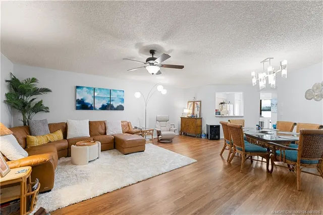a living room with furniture kitchen view and a chandelier