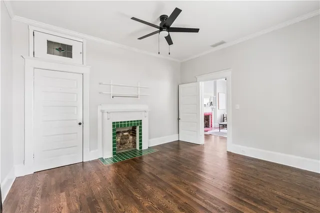 a view of an empty room with wooden floor fireplace and a window