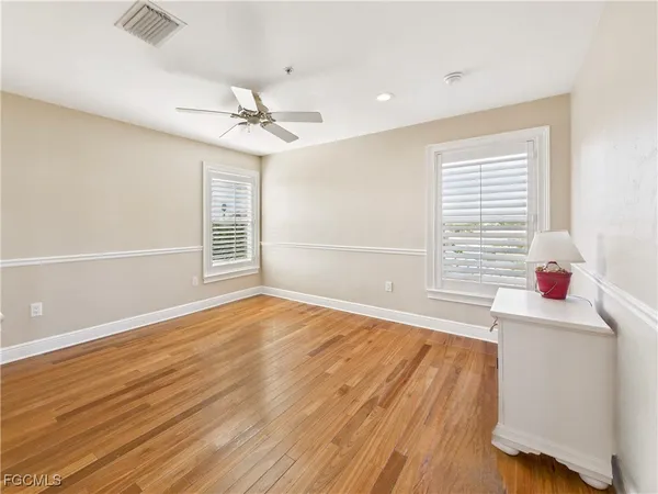 a view of an empty room with a window and wooden floor