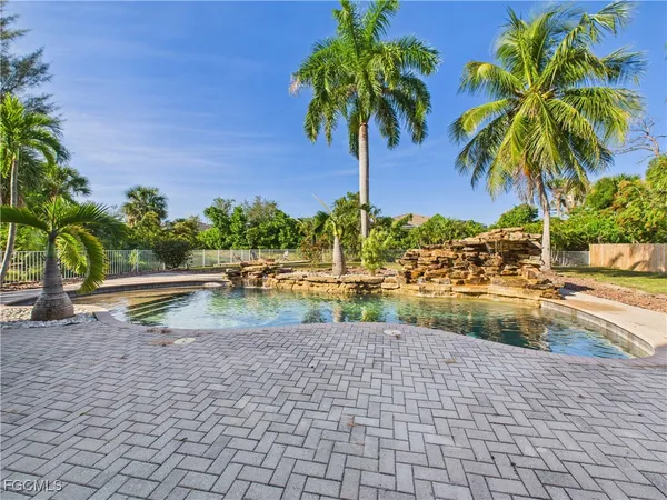a view of a swimming pool with a lawn chairs under palm trees
