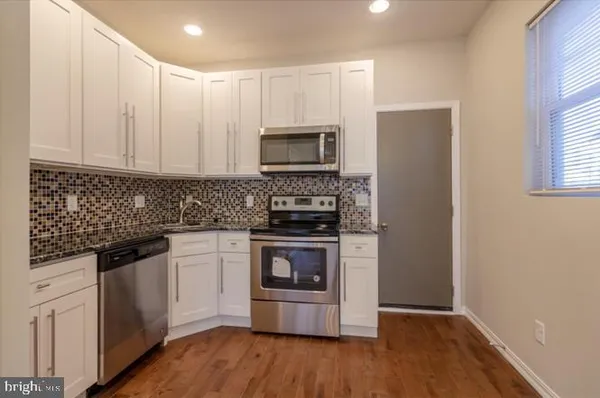 a kitchen with granite countertop white cabinets and stainless steel appliances