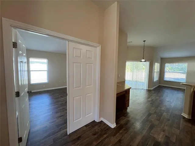 a view of an empty room with wooden floor and window