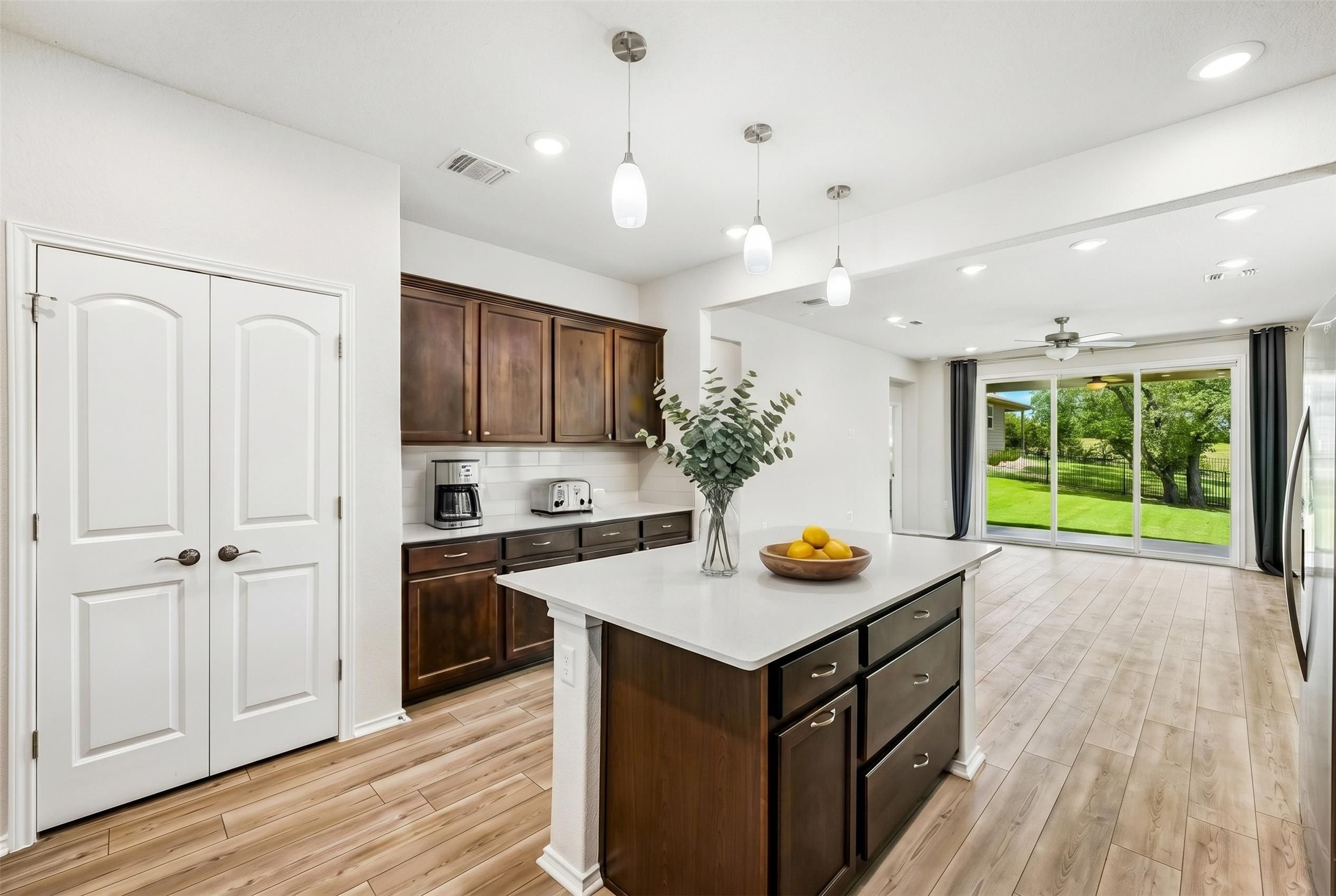 401 Yorktown Street Georgetown, TX 78633 - Photo 7 of 38 Kitchen island featuring a light-toned countertop, dark wood-finish cabinetry, and pendant lighting