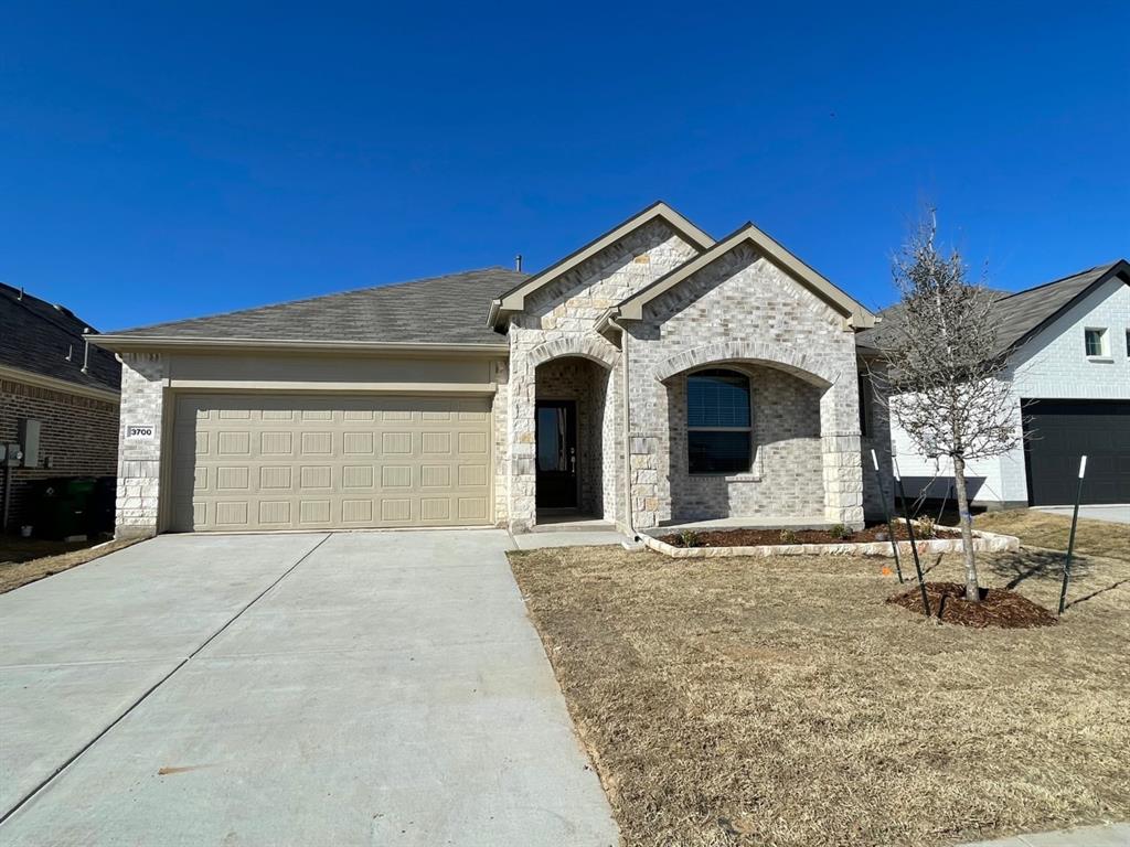 3700 Milkweed Road McKinney, TX 75071 - Photo 1 of 18 Single-story home featuring a light-toned brick facade with stone accents and an arched entryway