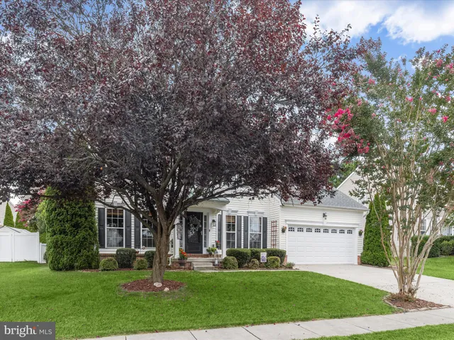 a front view of a house with a garden and trees
