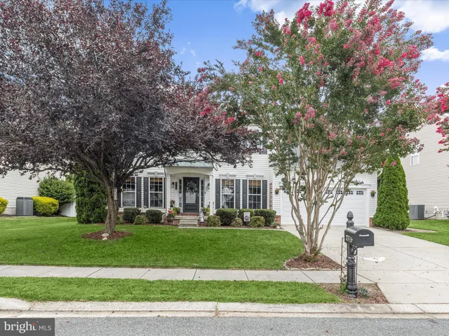 a front view of a house with a garden and tree