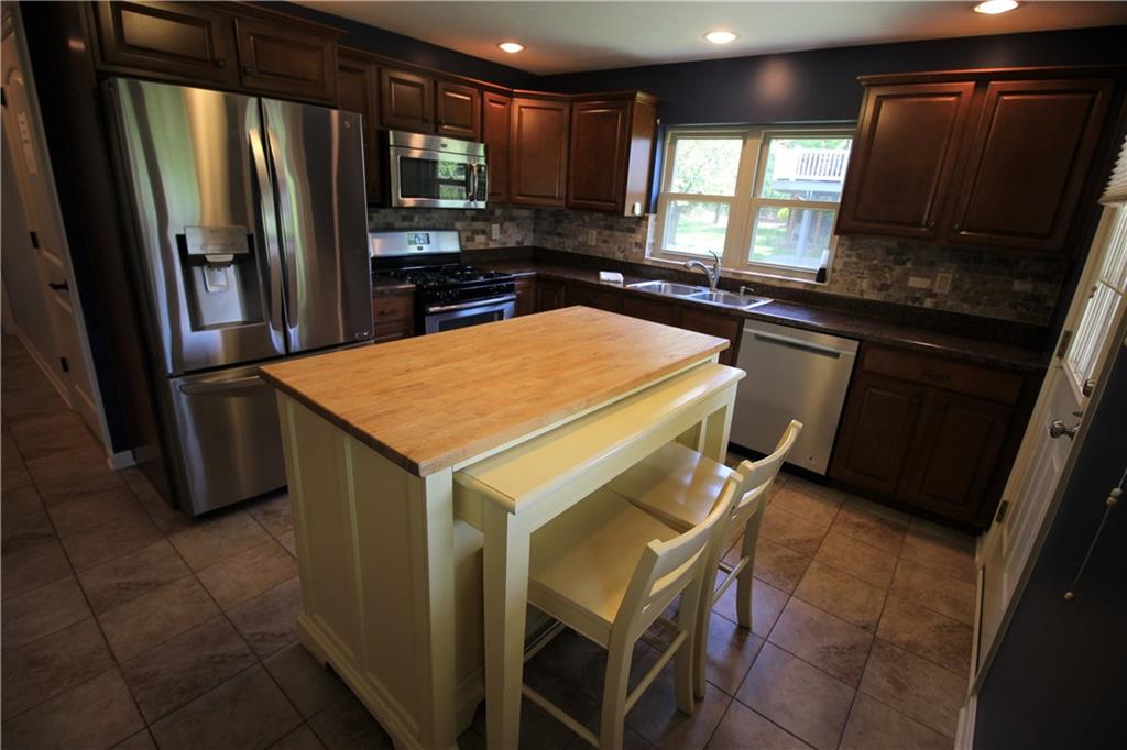 A fabulous gourmet kitchen  with stainless steel appliances, warm wood cabinetry, recessed lighting ceramic floor and island.What should we cook for dinner tonight?