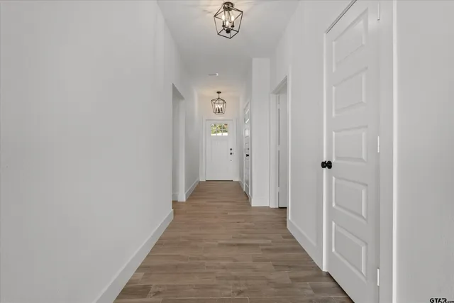 a view of a hallway with wooden floor and a chandelier