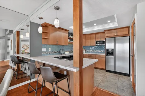 a kitchen with stainless steel appliances a stove a sink a refrigerator and chairs
