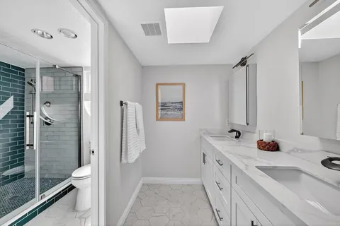 a bathroom with a double vanity sink toilet mirror and shower