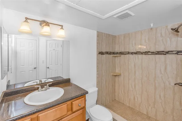 a bathroom with a granite countertop sink toilet a mirror and shower
