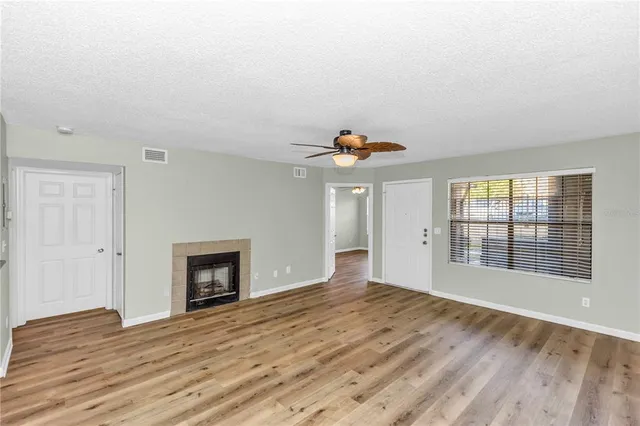 a view of empty room with wooden floor and fireplace