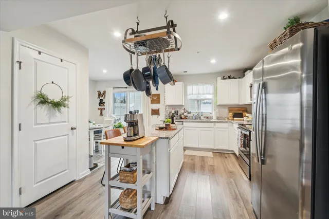 a kitchen with stainless steel appliances a refrigerator a stove a sink dishwasher and a dining table with wooden floor