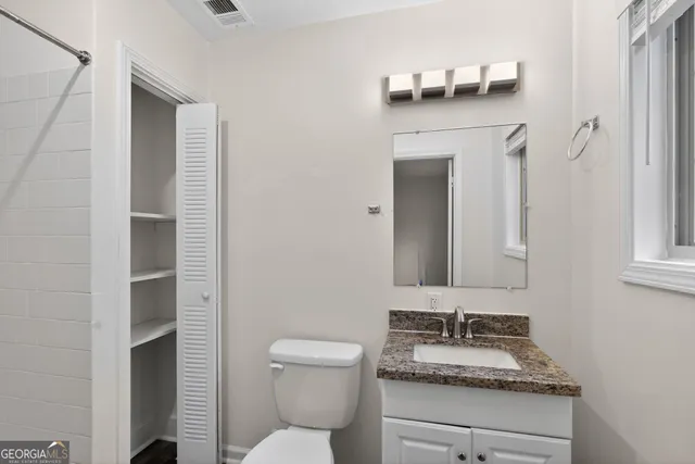 a bathroom with a granite countertop toilet sink and mirror