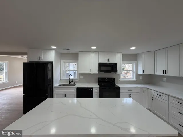 a kitchen with granite countertop a refrigerator and a stove top oven