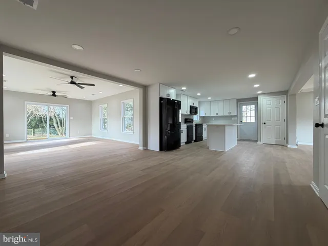 a view of an empty room with a window and kitchen view
