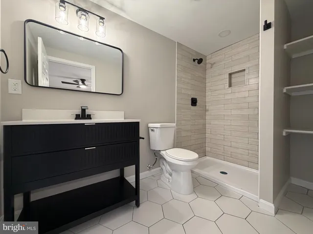 a bathroom with a toilet a sink a glass door shower and mirror