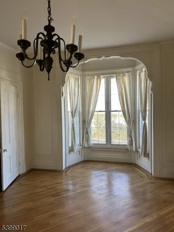 a view of an empty room with wooden floor fireplace and a window