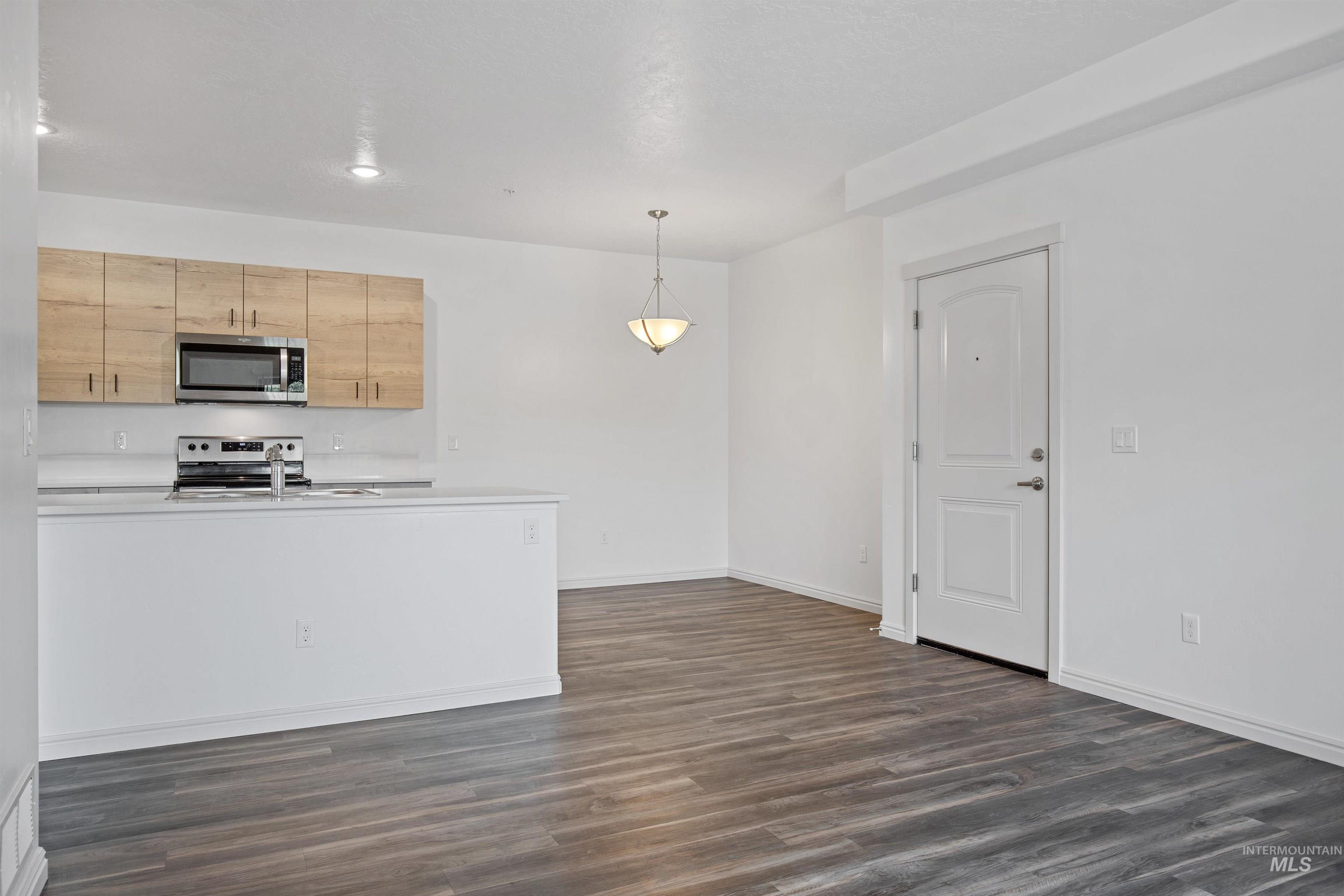 3126 East Victory Road Nampa, ID 83687 - Photo 5 of 9 Kitchen featuring stainless steel appliances, dark wood-type flooring, light countertops, decorative light fixtures, and light brown cabinetry