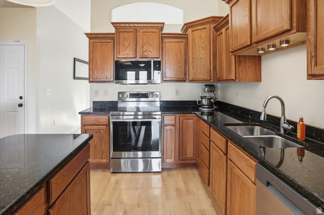 14820 175 East Draper, UT 84020 - Photo 6 of 39 Kitchen featuring stainless steel appliances, brown cabinets, dark stone counters, and light wood-style floors