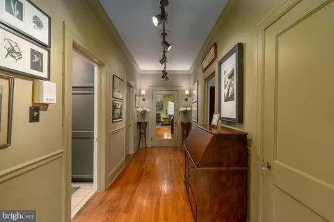 a view of a hallway with wooden floor and cabinets