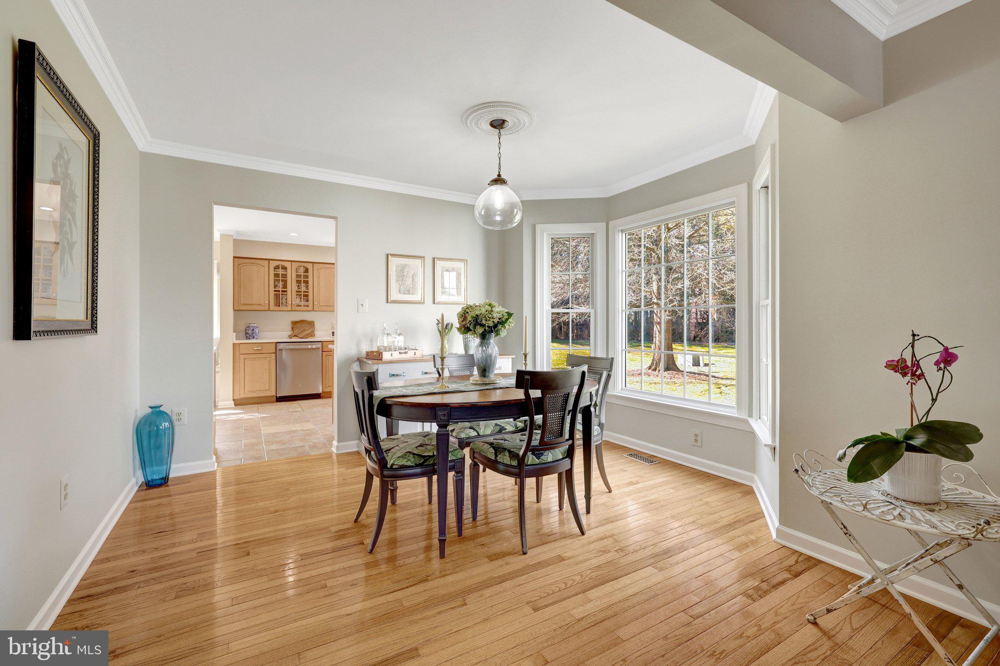 21039 Barcroft Way Sterling, VA 20164 - Photo 11 of 63 a dining room with wooden floor a chandelier a wooden table and chairs