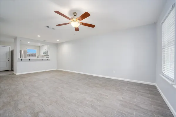 an empty room with a kitchen and a ceiling fan